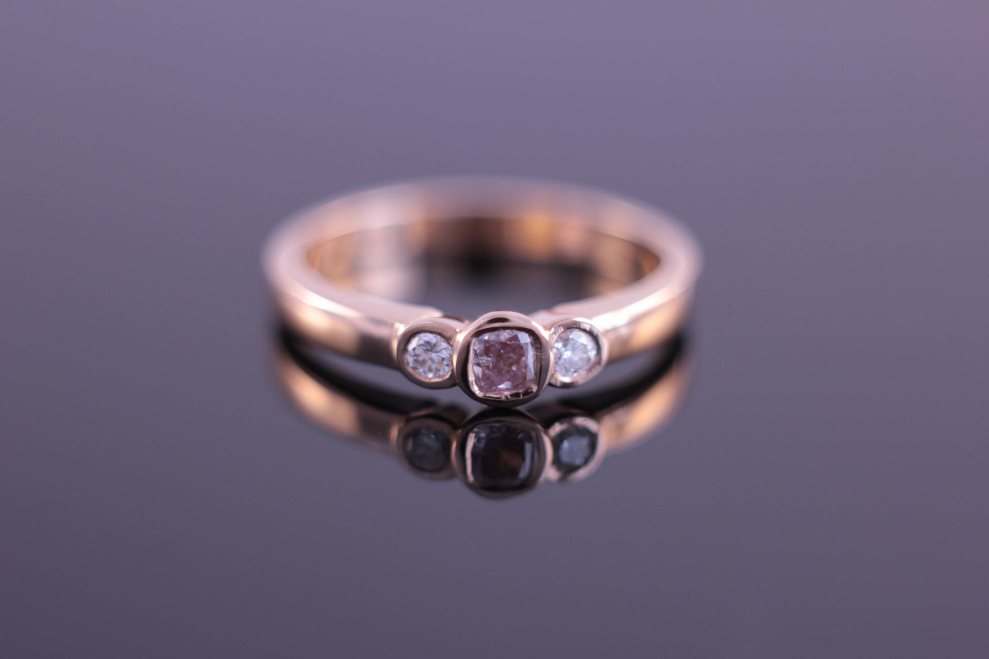 Three stone ring with rubover setting bezel set in rose gold